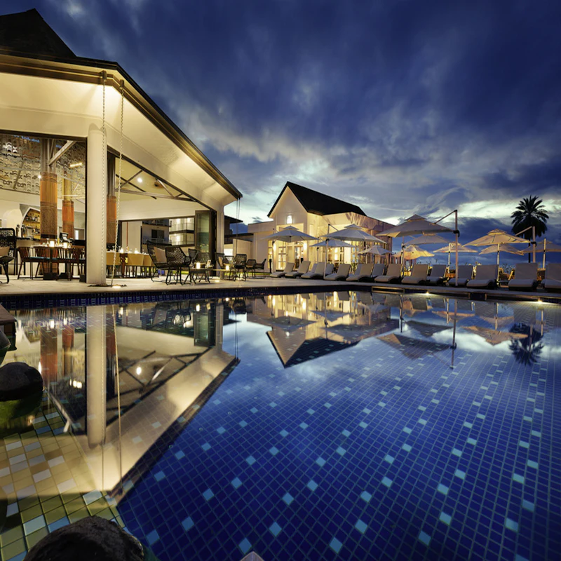 Resort iluminado ao anoitecer, refletido na piscina